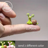 Two small green and brown miniature animal figurines shown being held by a hand.