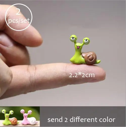 Two small green and brown miniature animal figurines shown being held by a hand.