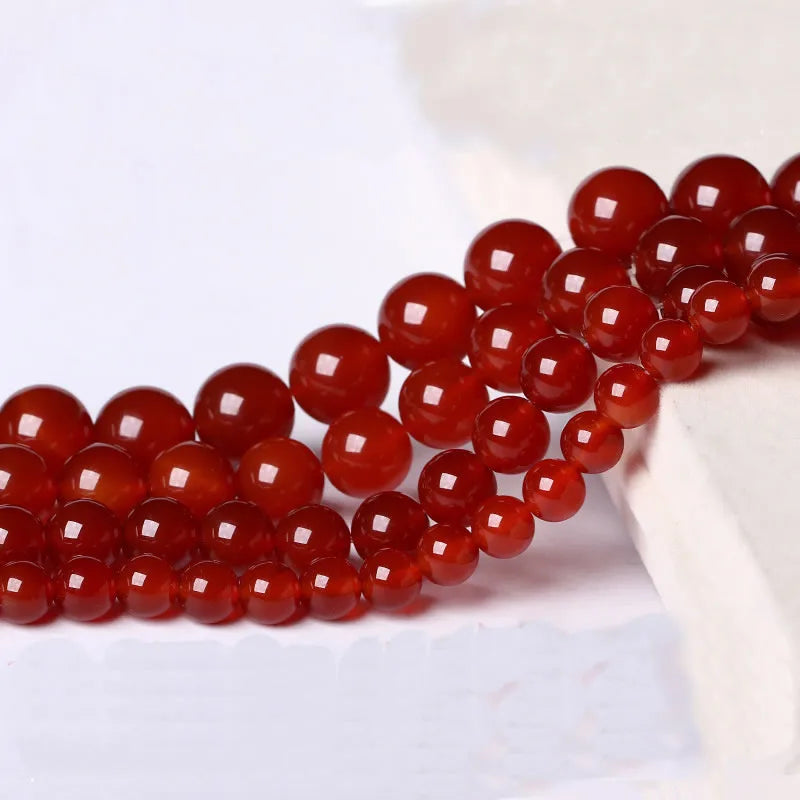 A string of round, polished natural red carnelian beads used for jewelry making.