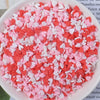 A bowl filled with heart-shaped fake candy sprinkles in shades of pink and red for slime and craft decorations.