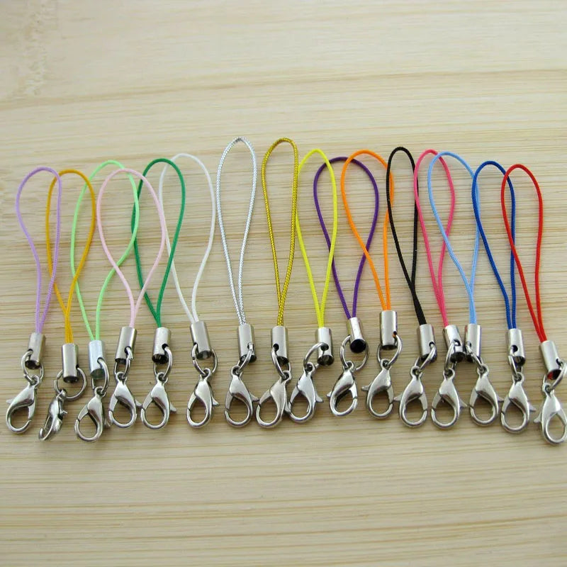 A collection of colorful lobster clasp keychains or charms arranged in a row on a light wooden surface.