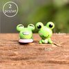 Two bright green miniature animal figurines sitting on a wooden surface.