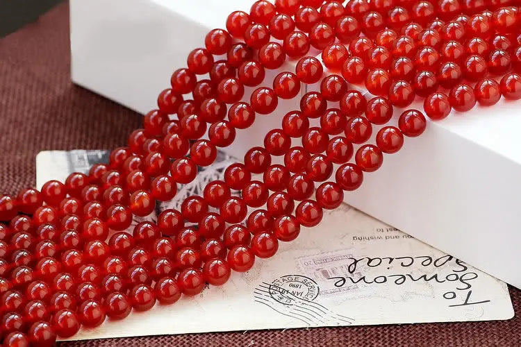 A close-up of strands of natural red carnelian round beads used for jewelry making