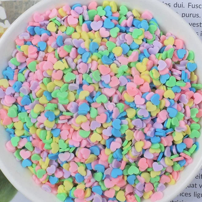 A bowl filled with heart-shaped fake candy sprinkles in various pastel colors like pink, blue, and green.