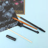 A set of five scratch art tools including a brush and a stylus laid on a light blue surface.