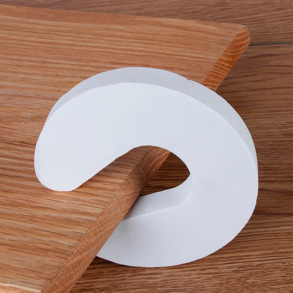 Tapón de puerta de EVA blanco con forma curva sobre una superficie de madera.