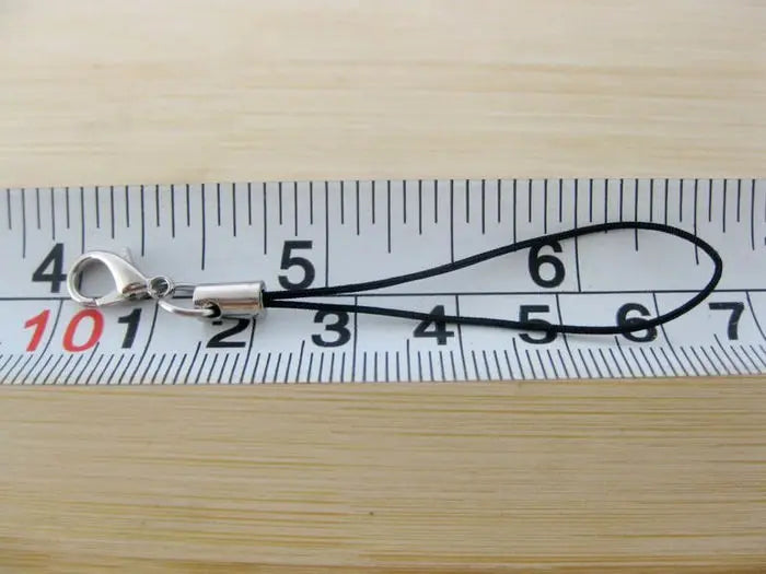 A silver lobster clasp keychain charm is measured against a ruler marked 1 through 7.