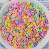 A bowl filled with heart-shaped fake candy sprinkles in various bright colors for slime and craft decorations