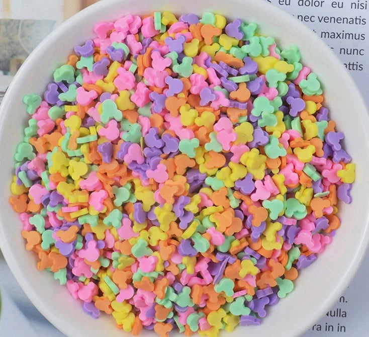 A bowl filled with heart-shaped fake candy sprinkles in various bright colors for slime and craft decorations