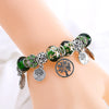A bracelet featuring green leaf and floral accents made of crystal charms on a wrist.