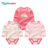 A set of three pink cotton baby bodysuits with long sleeves featuring colorful rainbow designs.