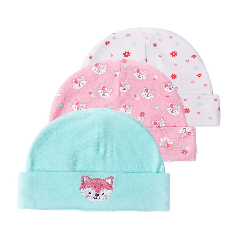Three knitted baby hats in pink, white, and light blue featuring cute fox cartoon designs.