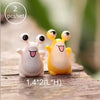 A set of two miniature animal figurines, one white and one yellow, sitting on a wooden surface.