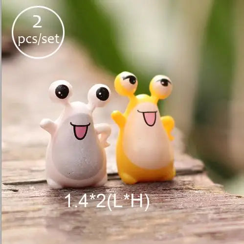 A set of two miniature animal figurines, one white and one yellow, sitting on a wooden surface.