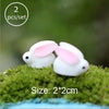 Two white rabbit figurines on green moss for fairy gardens or terrariums
