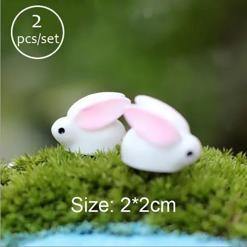 Two white rabbit figurines on green moss for fairy gardens or terrariums