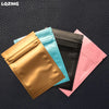 A collection of five mini reusable ziplock bags in gold, light blue, black, and pink, displayed on a dark surface.