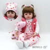 A baby doll with brown hair wearing a pink outfit and a pink dinosaur plush toy.