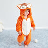 A baby wearing an orange and white animal hooded romper with ears, standing on a light blue rug.
