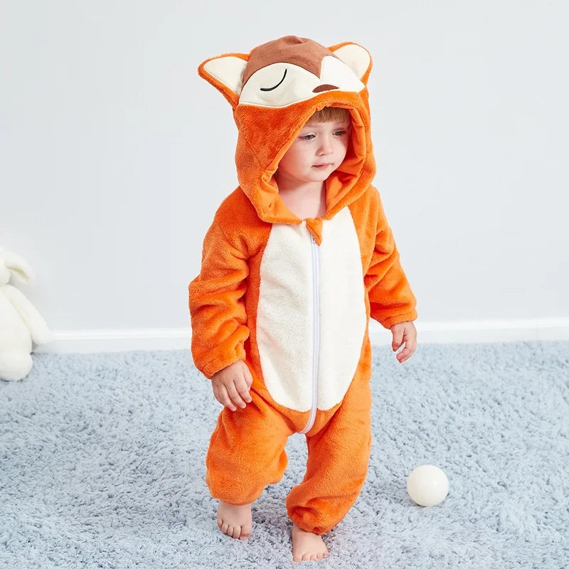 A baby wearing an orange and white animal hooded romper with ears, standing on a light blue rug.