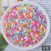 A bowl filled with heart-shaped fake candy sprinkles in various pastel colors like pink, blue, and yellow for crafting.