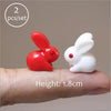 A pair of miniature red and white rabbit figurines shown on a person's finger, with a height of 1.8cm.