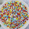A bowl filled with heart-shaped fake candy sprinkles in red, yellow, white, and blue for slime and craft decorations.