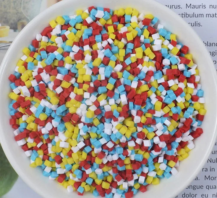 A bowl filled with heart-shaped fake candy sprinkles in red, yellow, white, and blue for slime and craft decorations.