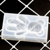 A white silicone mold shaped like a bear paw print for resin jewelry and crafts, resting on a black grid background.