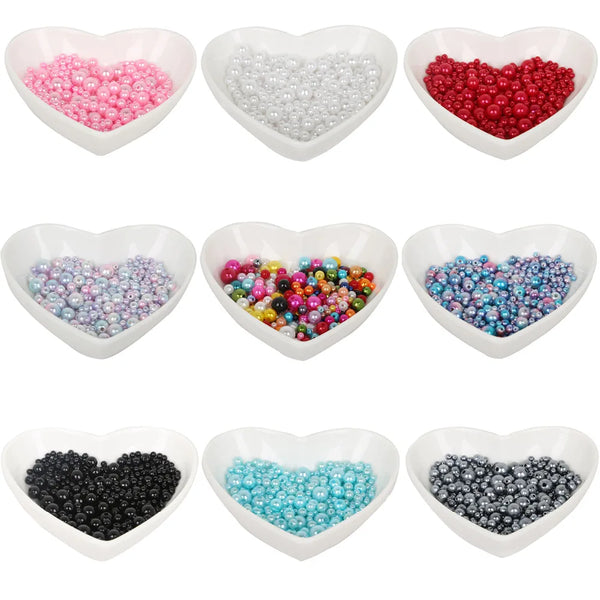 A collection of heart-shaped bowls filled with various colors of imitation pearl beads for DIY jewelry making
