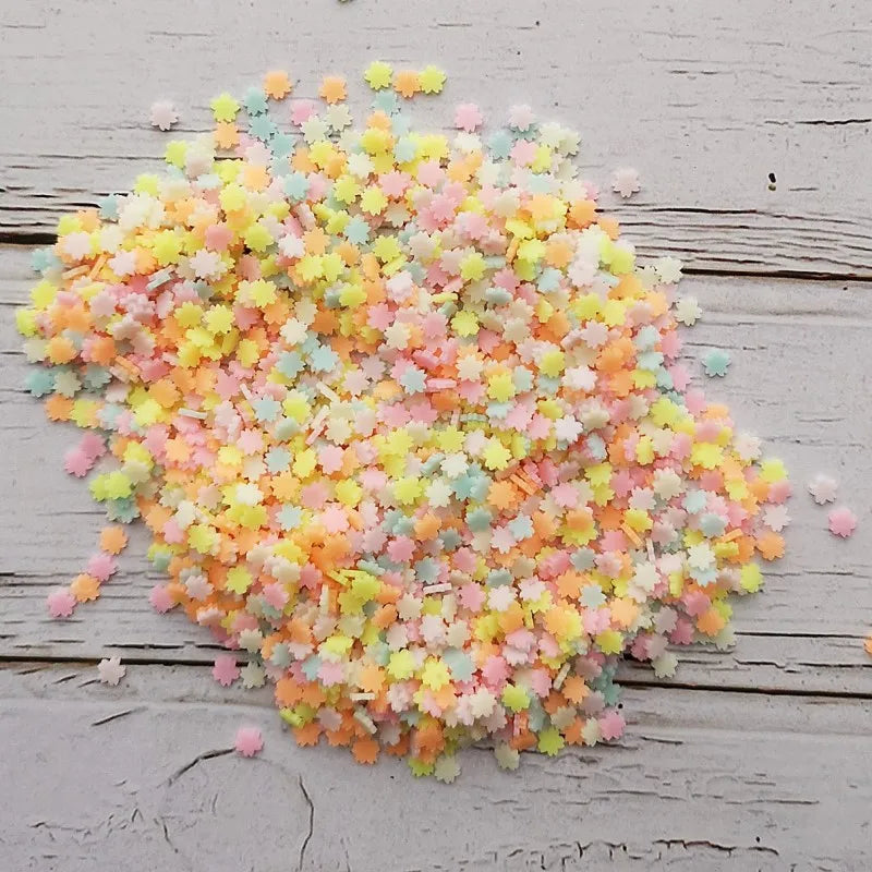 A pile of heart-shaped fake candy sprinkles in various pastel colors like pink, yellow, and blue on a wooden surface.