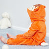 An adorable orange hooded romper for a baby lying on a light blue rug.