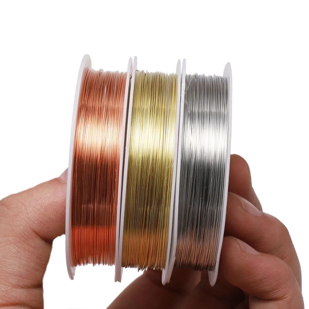 A hand holds a spool of durable copper beading wire for jewelry making in various colors.