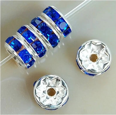 A string of blue crystal rondelle spacer beads for jewelry making, along with two separate silver-toned bead caps.