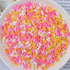 A bowl filled with heart-shaped fake candy sprinkles in pink and yellow colors for slime and craft decorations