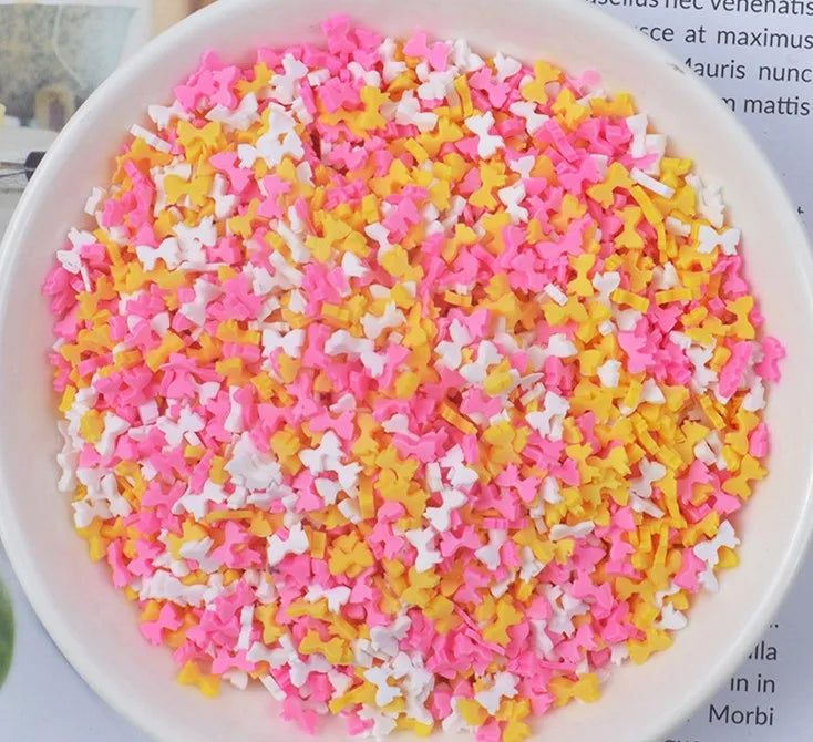 A bowl filled with heart-shaped fake candy sprinkles in pink and yellow colors for slime and craft decorations
