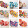 Various colors of heart-shaped fake candy sprinkles for slime and craft decorations are shown in glass jars and scattered on 