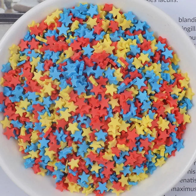 A bowl filled with heart-shaped fake candy sprinkles in red, orange, yellow, and blue for slime and craft decorations.
