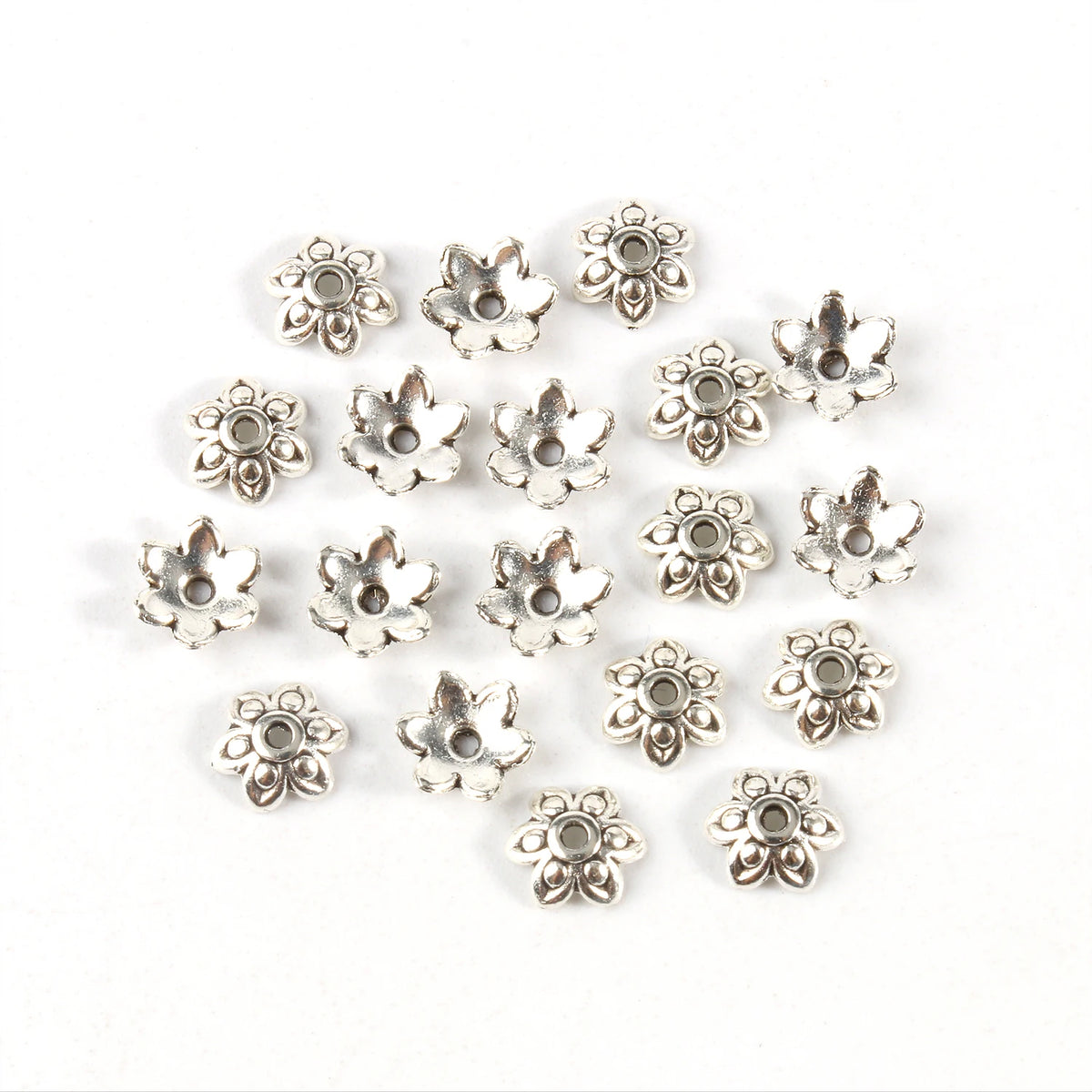 A collection of silver Tibetan style hollow flower bead caps for jewelry making.