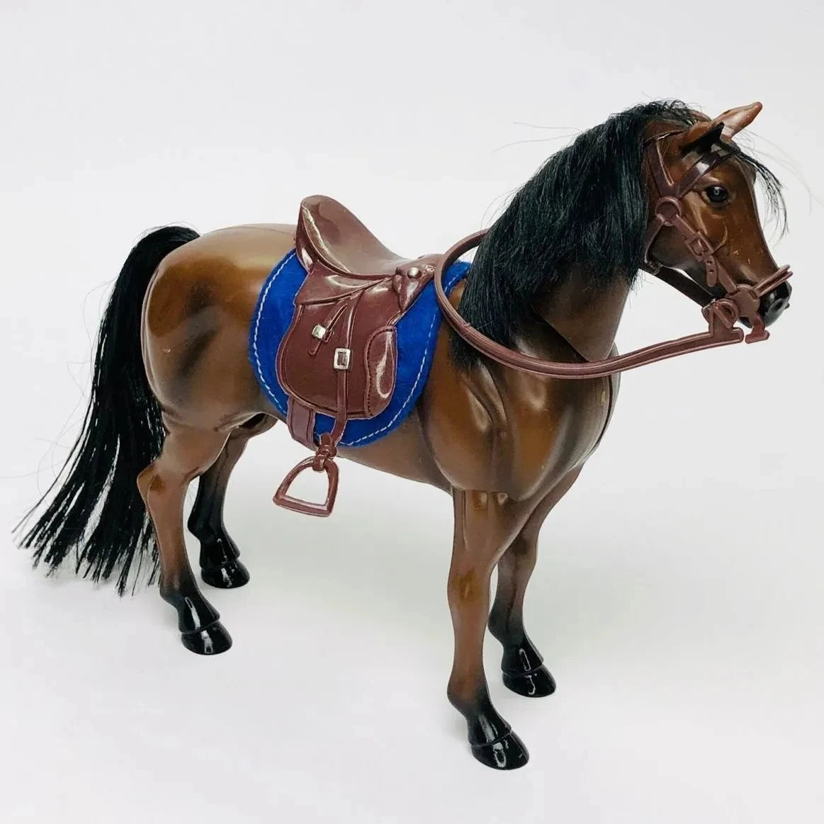 A 1/12 scale dollhouse horse with a brown coat wearing a brown leather saddle and riding prop.