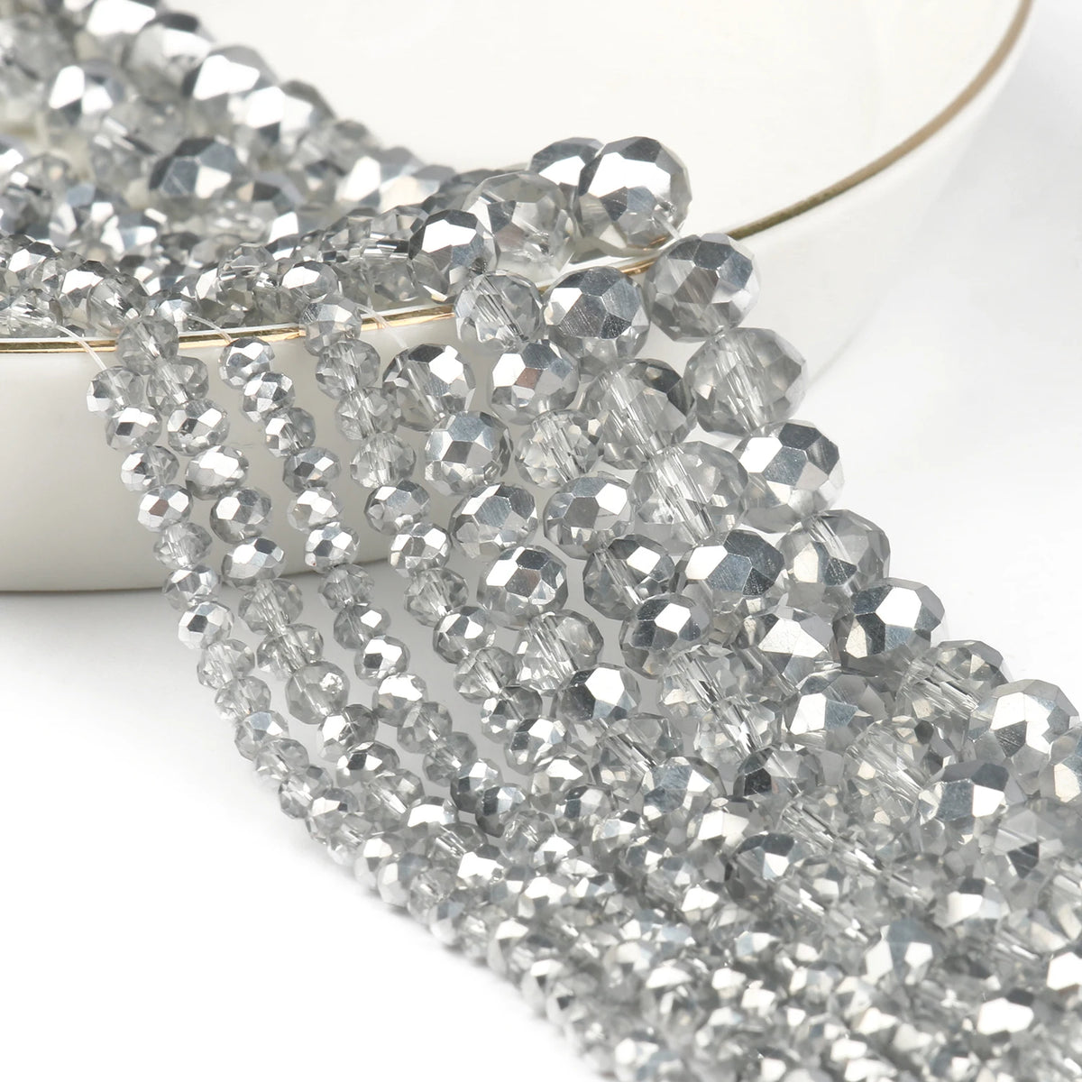 Silver faceted crystal glass beads strung together on a white background