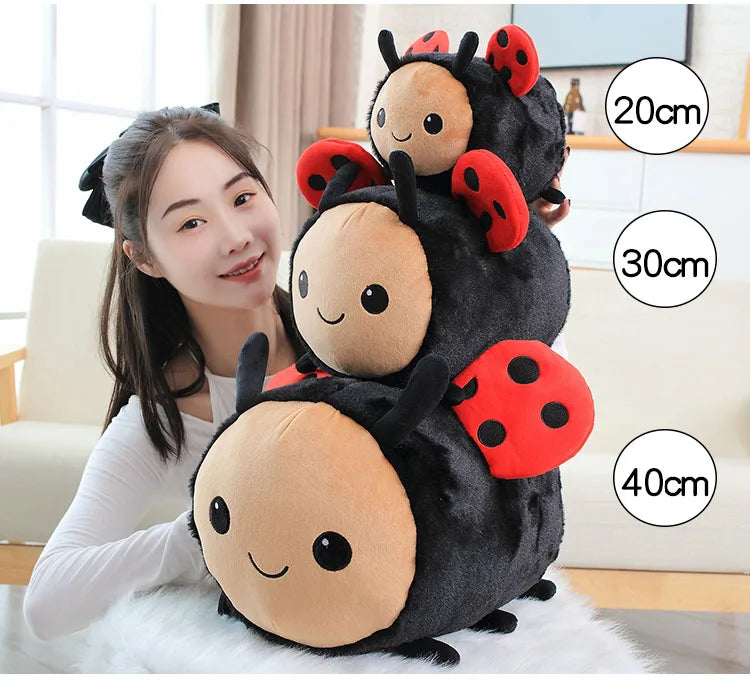 A woman is holding a plush toy of a black bee with red ladybug spots, showing various sizes.