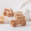 A small wooden toy car and a larger white silicone hand are visible on a white surface.