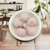 A white bowl filled with pink fluffy mink fur pom poms for crafts and accessories