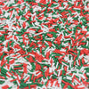 A close-up view of red, white, and green candy sprinkles scattered on a surface.