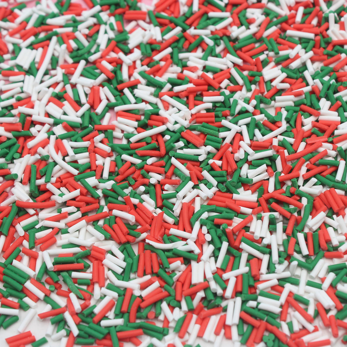 A close-up view of red, white, and green candy sprinkles scattered on a surface.