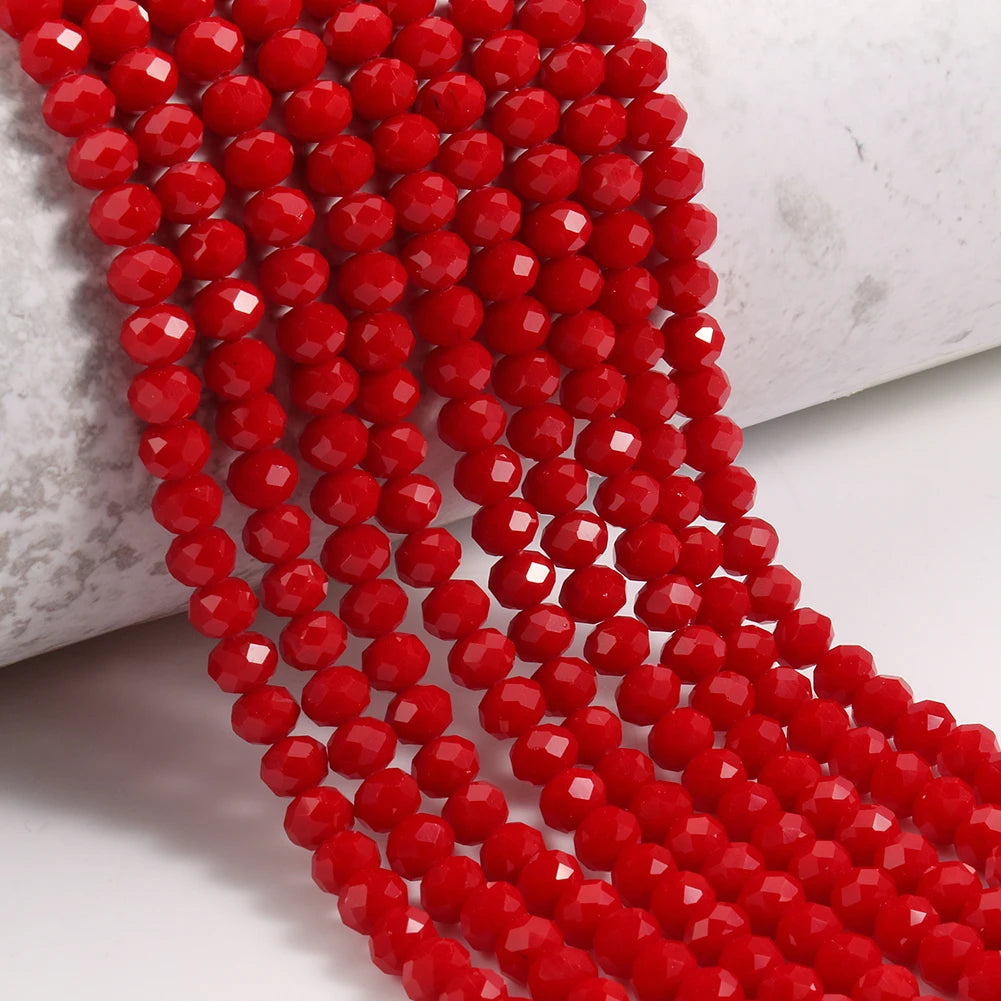 A close-up of a strand of bright red faceted crystal glass beads for jewelry making