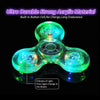 A glowing green acrylic fidget spinner with multiple light modes resting on a reflective surface.