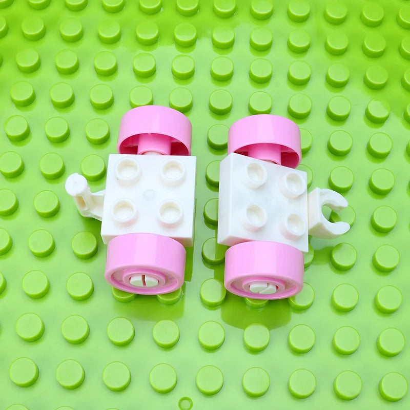A set of pink and white city traffic vehicle building blocks with trucks and buses placed on a bright green grid surface.