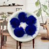 A white bowl filled with bright blue fluffy mink fur pom poms for crafts and accessories.